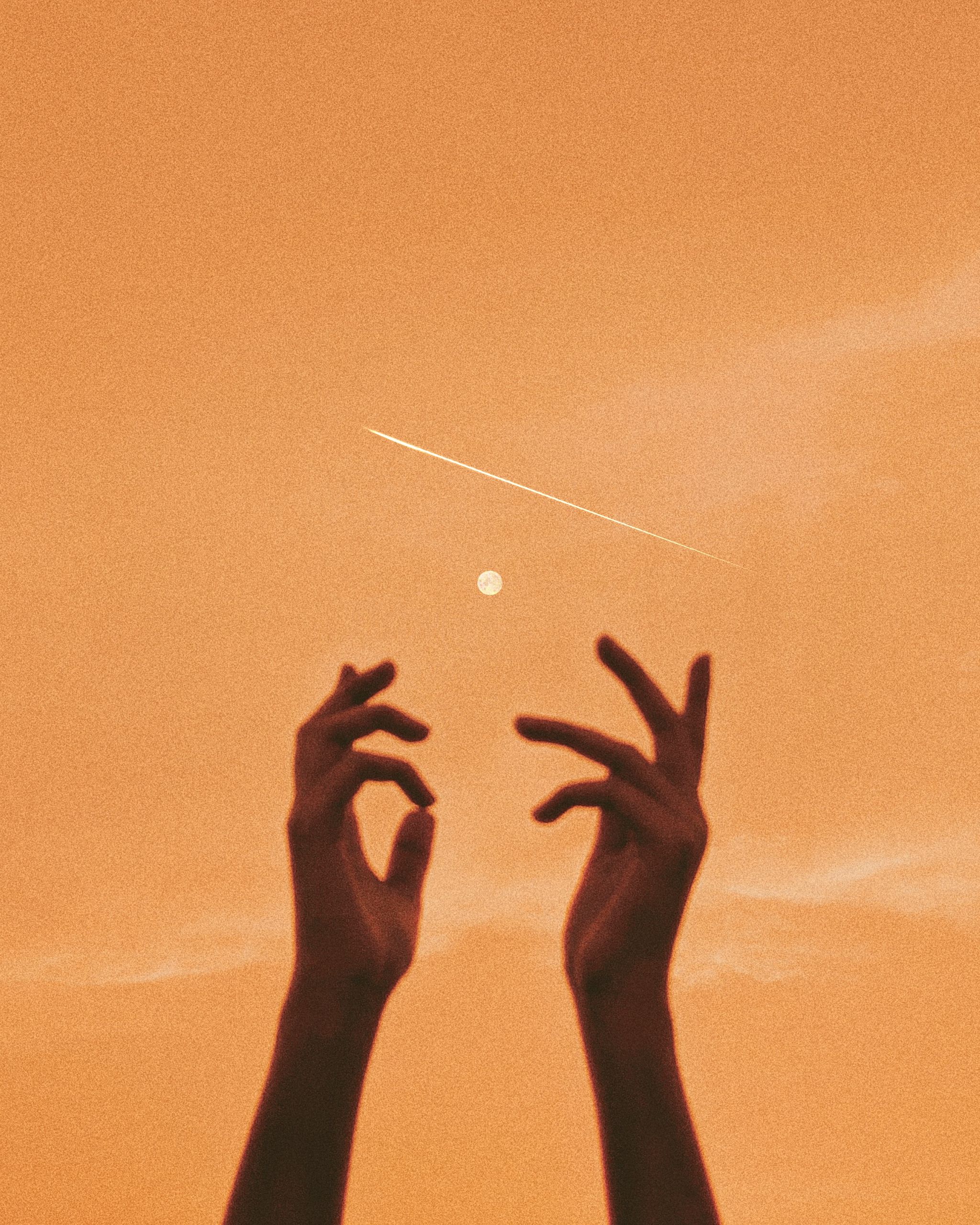 Silhouetted hands reaching up towards the moon and a shooting star in a warm orange sky.